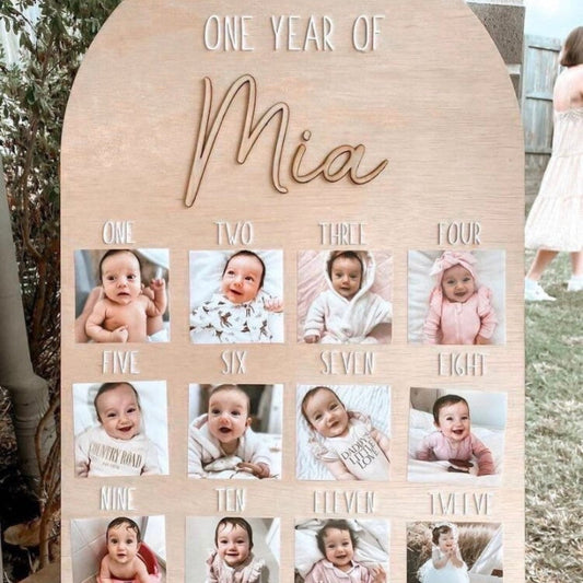 Wooden photo display with 'One Year of Mia' text and baby photos arranged in a grid.
