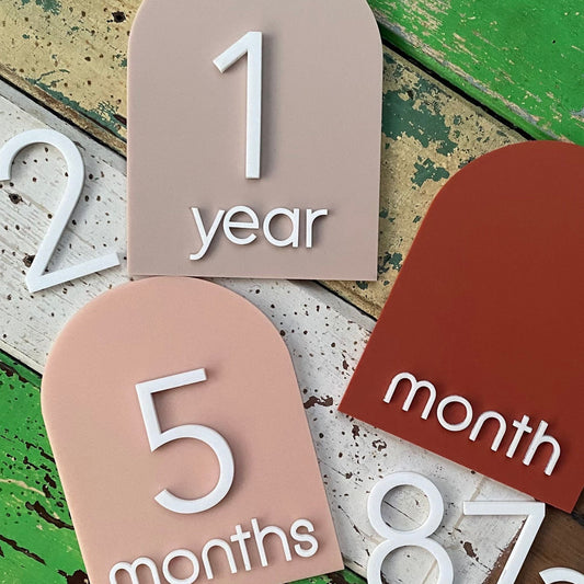 Baby milestone markers on a rustic wooden background