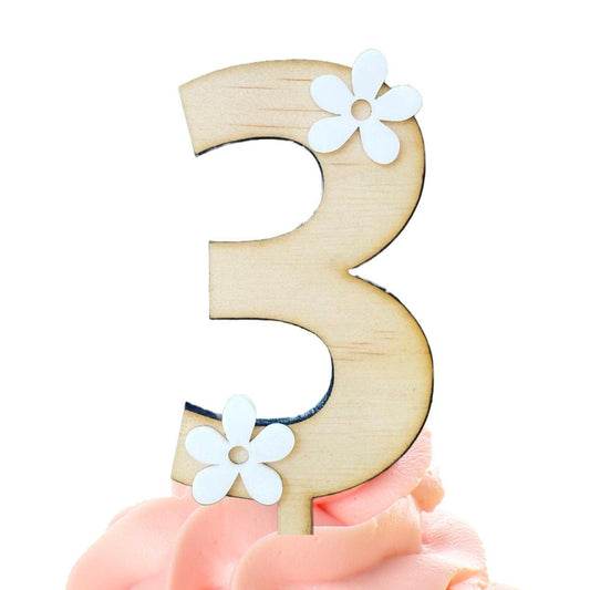 Cupcake with pink frosting and a wooden number 3 decoration on a white background