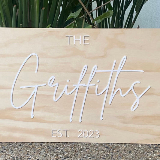 Wooden sign with 'The Griffiths EST. 2023' text against a natural background